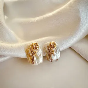 Detailed view of elegant natural baroque pearl earrings with golden rose flower.