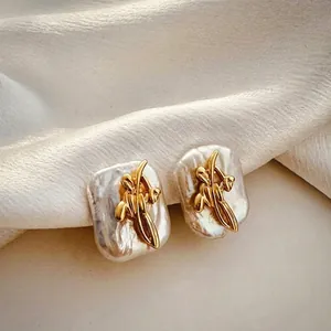 Elegant macro view of gold flower accents on irregular white Baroque pearl earrings