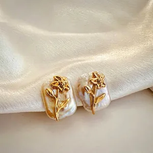 Close-up view of the elegant 18K gold flower design on natural baroque pearl earrings