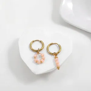 Close-up detail of asymmetric gold stainless steel hoop earrings with peach crystal beads