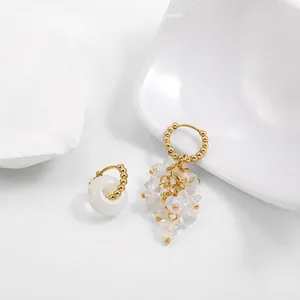 Detailed view of the asymmetrical hoop earrings with white translucent stone clusters.