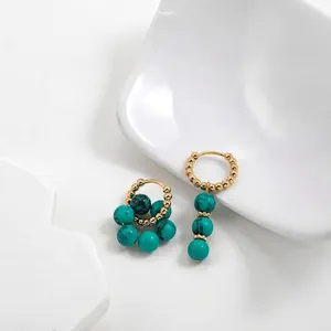 Close-up of asymmetric French vintage turquoise earrings in stainless steel hoops.