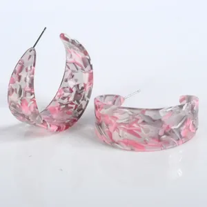 Dettaglio di orecchini a cerchio in acrilico marmorizzato rosa e bianco
