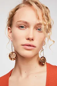 Modella indossa eleganti orecchini a cerchio in acrilico tartarugato e oro.