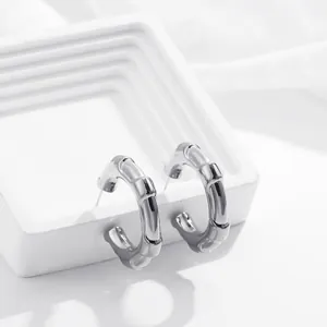 Dettaglio di orecchini a cerchio in acciaio inox argento con design moderno a bambù