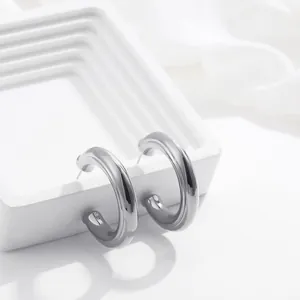 Dettaglio di orecchini a cerchio grossi a forma di U in acciaio inox lucidato.