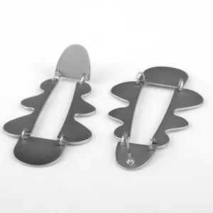 Dettaglio posteriore di orecchini pendenti geometrici in argento opaco da donna.