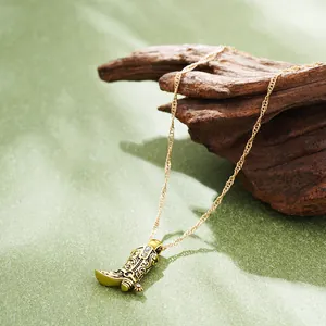 Vintage 18K gold plated stainless steel cowboy boot pendant necklace on green background