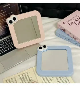 Detalle de espejos de maquillaje cuadrados en rosa y azul con diseño de ojos lindos