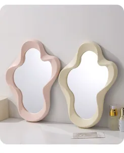 Paar cremefarbene wellenförmige Wolkenspiegel in Rosa und Beige auf einem Schminktisch