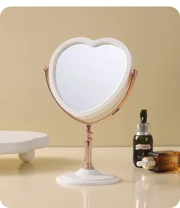 Vintage heart-shaped tabletop makeup mirror with elegant rose gold metal stand detail.