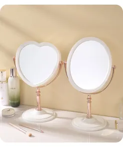 Detail shot of vintage rose gold heart and oval makeup mirrors on a white vanity table