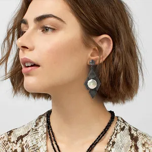 Dettaglio di eleganti orecchini a rombo neri con perla indossati da una modella