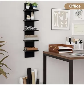 Close-up of a black multi-tier floating wall shelf displaying books and decor in an office.