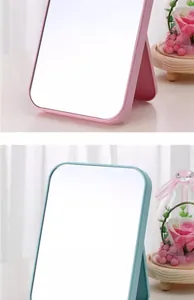 Detail view of pink and blue foldable desktop makeup mirrors with adjustable stand.