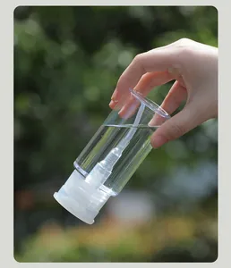 Gros plan d'un flacon pompe de voyage transparent rempli de liquide dans la nature
