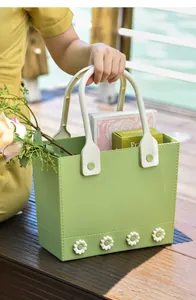 Detail view of a green portable storage basket with flower decor held outdoors