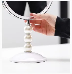 Nahaufnahme eines luxuriösen doppelseitigen Schminkspiegels mit elegantem Perlenständer Design.