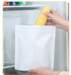 Poniendo maíz fresco en una bolsa de papel de aluminio blanco en un refrigerador.