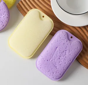 Detailed view of yellow and purple wood pulp sponges on a wooden tray