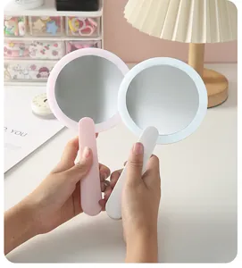 Specchi per trucco portatili a LED in rosa e bianco mostrati in un accogliente ambiente desktop.