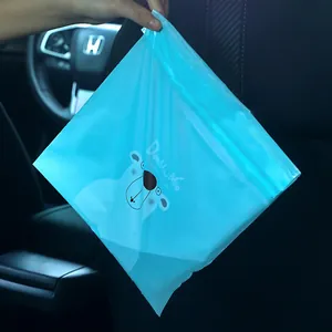 Blue disposable self-adhesive car trash bag with cute bear design hanging in a car interior