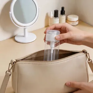 Portable clear plastic travel pump bottle being placed into a stylish beige handbag for travel