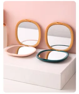 Detail view of two open square folding portable makeup mirrors on a white pedestal.