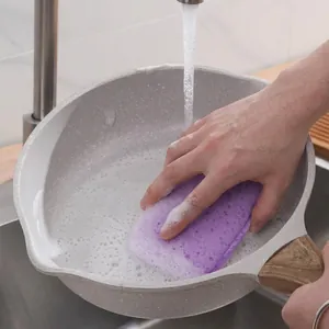 Durable purple wood pulp cotton sponge scrubbing a grey non-stick pan in a sink