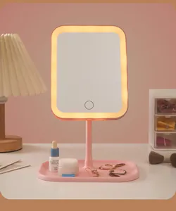 Nahaufnahme eines rosa LED-Schminkspiegels mit warmem Licht auf einem weißen Tisch