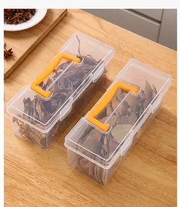 Detail view of transparent seasoning storage boxes with orange handles on a wooden table