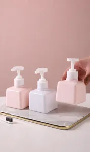 Detailweergave van roze en witte vierkante hervulbare lotionpompflessen op een dienblad