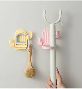 Detail of cactus-shaped wall hooks holding a wooden brush and a mop handle.