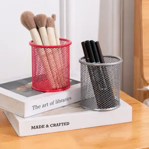 Gros plan de porte-stylos en maille métallique rose et argent sur des livres décoratifs.
