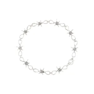 Macro detail of a silver-toned barbed wire thorn necklace in hip-hop punk style on white.