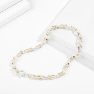 Detailed macro view of two-tone silver and gold gauge link necklace on minimalist white background