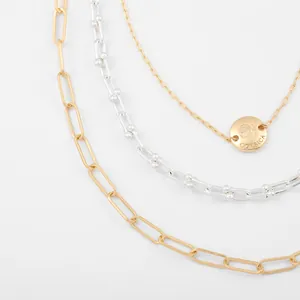 Close-up detail of layered gold and silver chains with engraved Corsica pendant