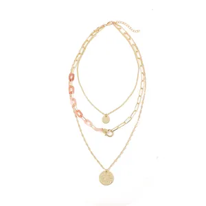 Detailed macro shot of a multilayered gold necklace with peach resin links and pendants