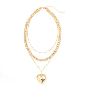 Detailed view of layered gold necklace with polished heart pendant in hip-hop style