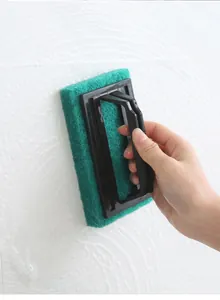 Close-up detail of cleaning brush with handle removing foam from white bathroom tiles