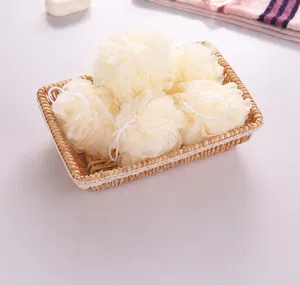 Éponges de bain en maille crème douce soigneusement disposées dans un panier tissé pour déco
