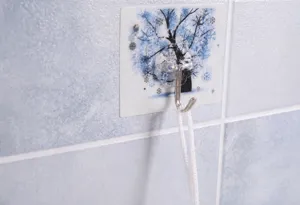 Détail d'une fleur de douche blanche suspendue à un crochet adhésif motif arbre bleu