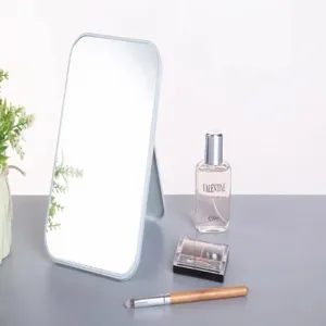 Miroir de maquillage carré pliable sur une coiffeuse avec du parfum et un pinceau