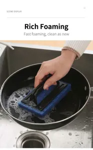 Macro view of a handheld sponge brush cleaning a frying pan inside a stainless steel sink
