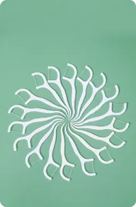 Detailansicht weißer Zahnseide-Sticks, die in einem dekorativen Spiralmuster angeordnet sind.