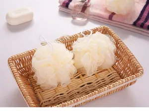 Close-up view of two soft cream mesh bath sponges with white hanging loops in a wicker basket.
