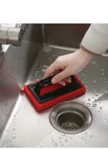 Action detail of the red sponge cleaning brush scrubbing a stainless steel sink