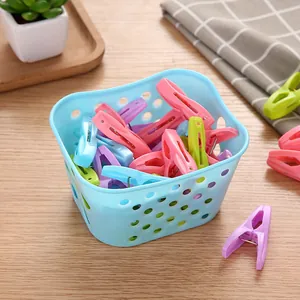 Colorful set of 30 plastic clothespins with blue storage basket on wooden surface