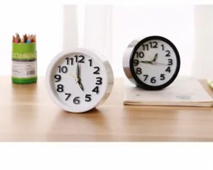 Mini minimalist round alarm clocks in black and white displayed on a wooden desk