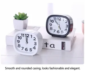 Minimalist round alarm clocks in black and white shown on a white desk with decor